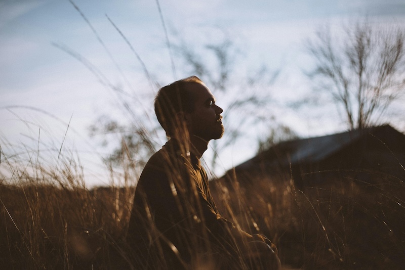 a man meditating in a field of grass as a strategy to improve mental vitality