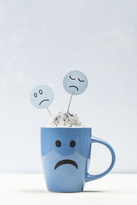 a mug with a sad face on it and two signs with sad faces