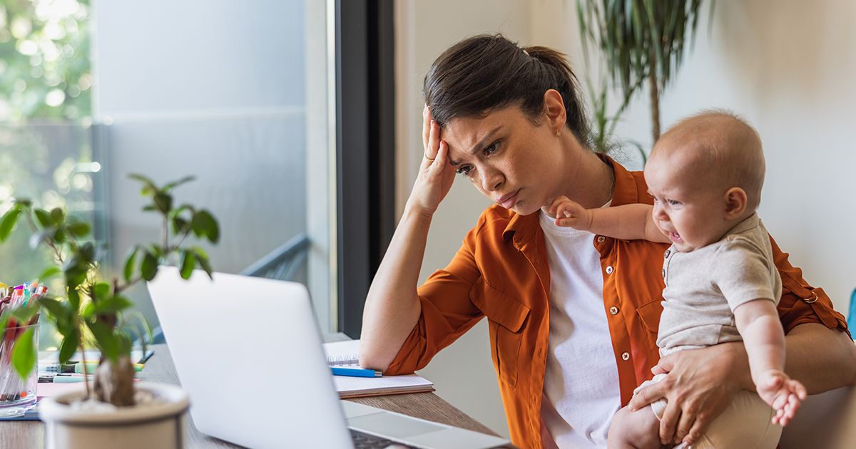 a woman sits at her computer and appears stressed