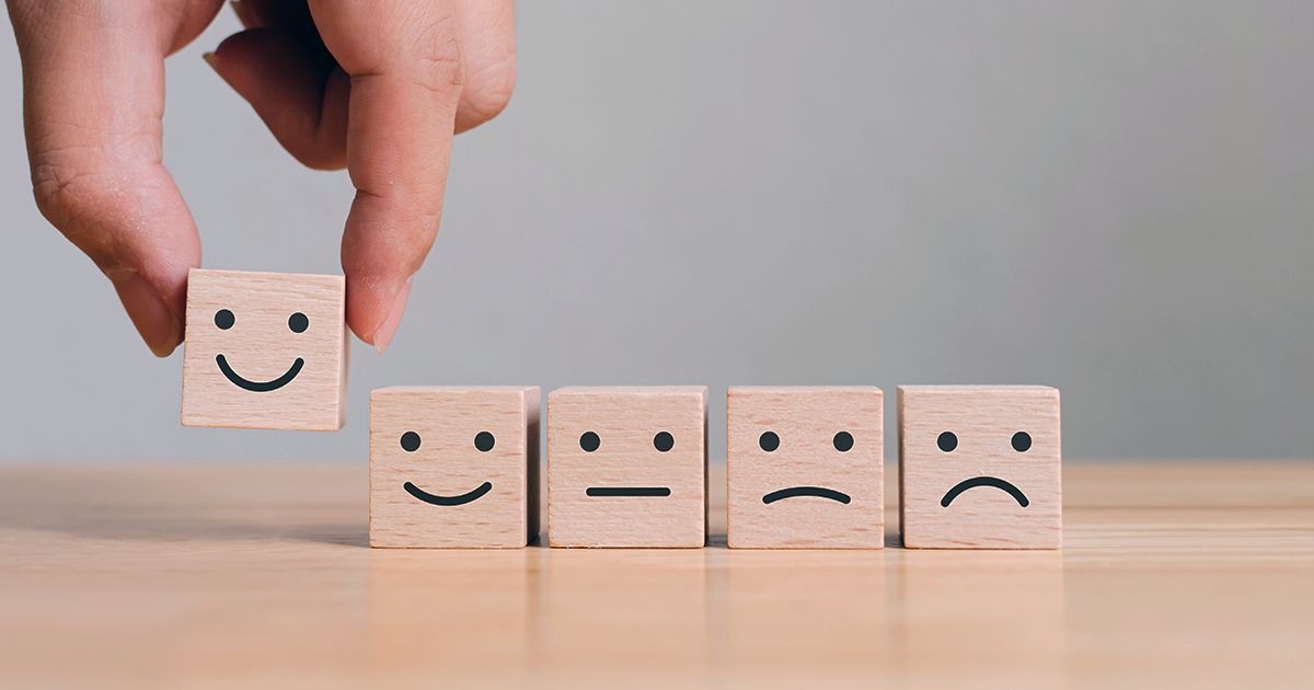 emotional mastery header a hand selecting a happy face from a row of blocks, illustrating emotional mastery